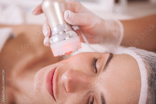 Cropped close up of a female client getting rf-lifting procedure by professional dermatologist. Attractive woman receiving facial skincare treatment