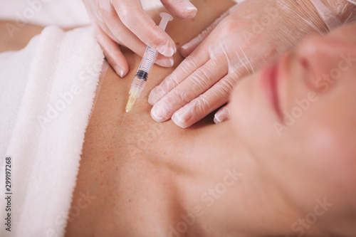 Cropped close up of a cosmetologist injecting filler fluid into chest skin of a female client. Woman getting skin rejuvenating injections by cosmetologist