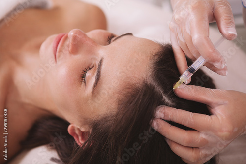 CLose up of a woman getting vitamin injections in her scalp. Female client receiving hairloss treatment by professional dermatologist