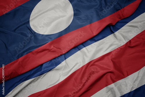 waving colorful flag of costa rica and national flag of laos.