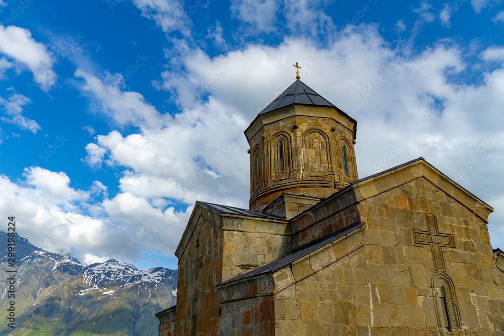 Fototapeta premium Gergeti Trinity Church, Georgia. Sunrise at the Gergeti Trinity Church with sunrays at chapel at the foot of Kazbegi mountain near Stepantsminda