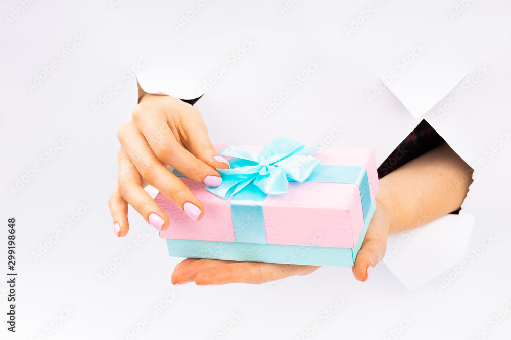 Pink gift with a blue ribbon in hands with manicure. Christmas. Paper Cut. Pink gift with a blue ribbon in hands with manicure. Christmas. Paper Cut.