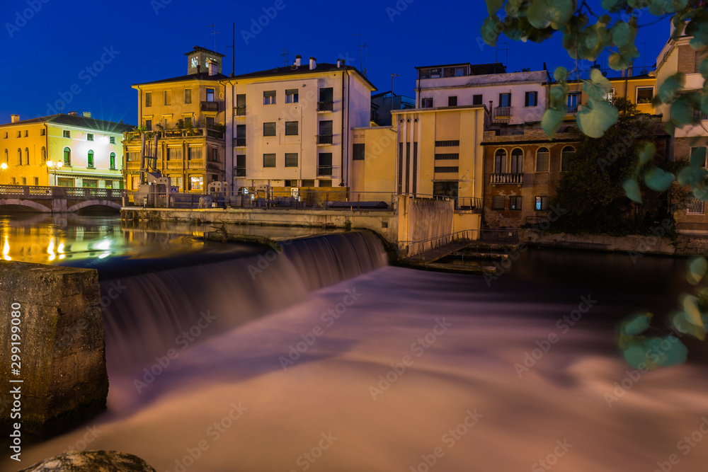 View on waterfall and a dam on Sile river with beautiful blue sky at night Treviso Italy
