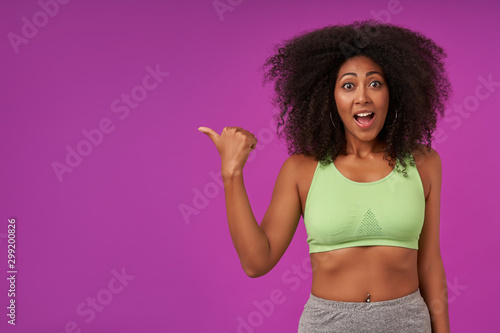 Tableau sur toile Indoor photo of overjoyed young curly woman with dark skin wearing casual hairst