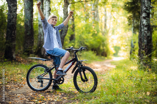 Boy riding a bike outdoors in the grass on a sunny day with hands raised