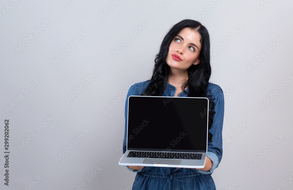 Young woman with a laptop computer in a thoughtful pose on a gray background Young woman with a laptop computer in a thoughtful pose on a gray background