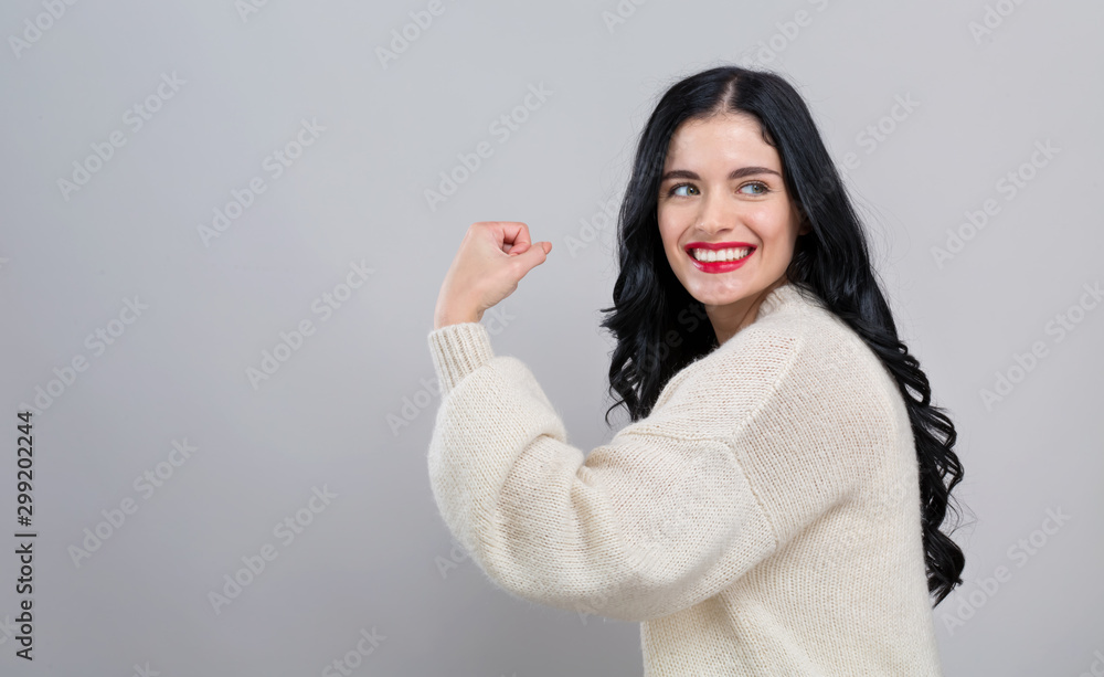 Powerful young woman in a success pose on a gray background Powerful young woman in a success pose on a gray background