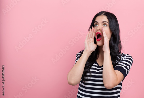 Young woman shouting on a pink background