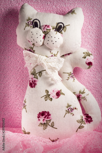 Self made soft toy. Handmade cat. Manual sewing white with pink flowers toy cat. A fun, soft toy made with your own hands.