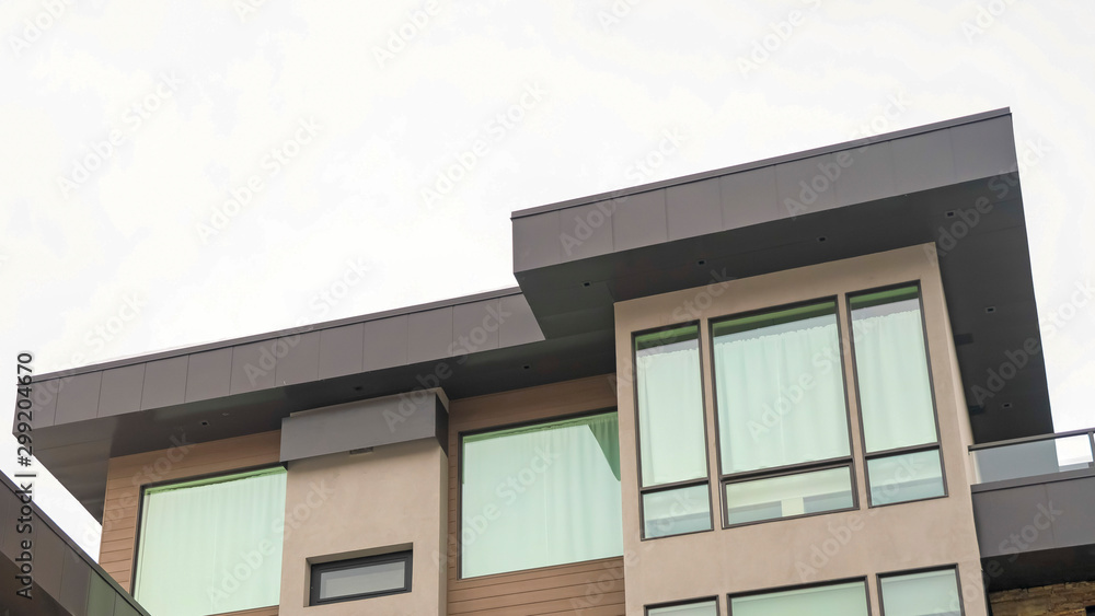 Panorama frame Exterior of a modern home with flat rooftop large windows and stone wall