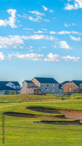Vertical frame Golf course and houses with distant mountain and blue sky view on a sunny day © Jason