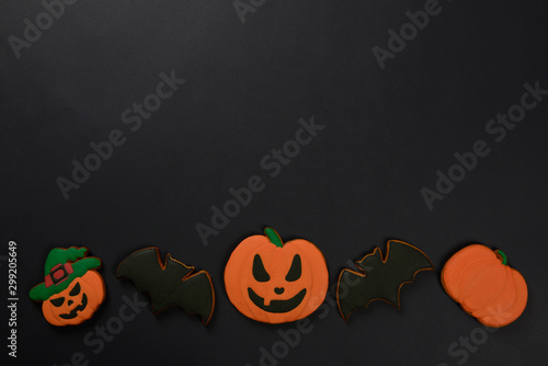 The hand-made eatable gingerbread Halloween pumpkins and bats on black background photo