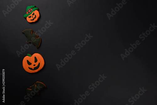 The hand-made eatable gingerbread Halloween pumpkins and bats on black background photo