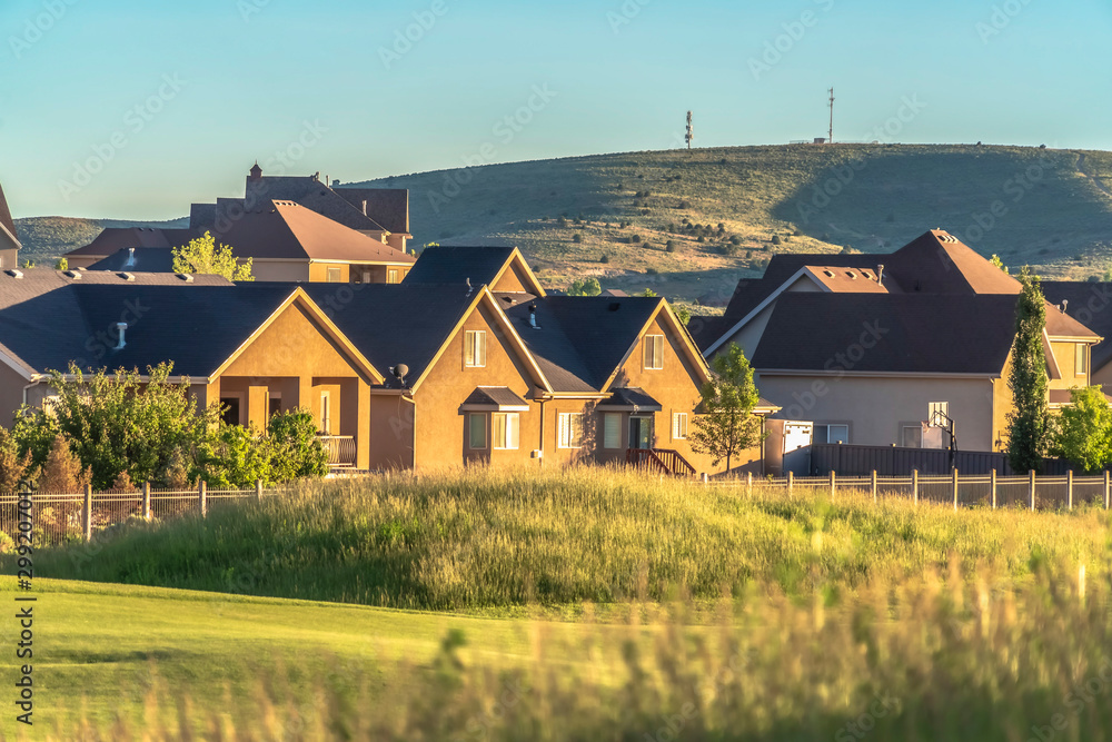 Sunlit hazards and fairway of a golf course with houses and hill background Sunlit hazards and fairway of a golf course with houses and hill background