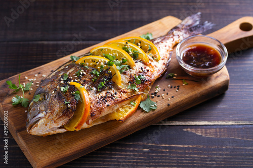 Quadro em tela Orange ginger sea bream fish, sprinkled with sesame seeds and cilantro on serving board