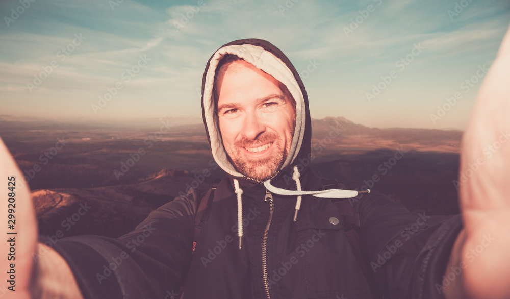 Happy man making a selfie by phone with mountains in the background ...