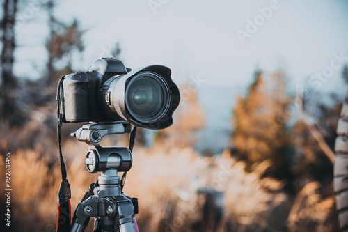 Camera on a tripod makes timelaps or records a video. Shallow depth of field. Warm photo filter and noise.