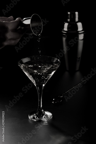 A hand pooring martini  to a cocktail glass with cocktail shaker and a spoon. photo