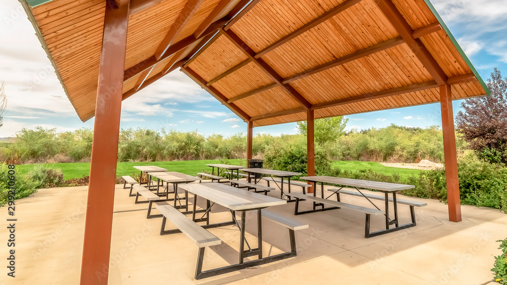 Panorama frame Sunny day at a park with view of tables and benches under a picnic pavilion