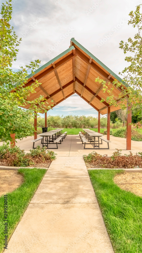 Vertical Beautiful view of a picnic pavilion at a park with pathway and trees in front Vertical Beautiful view of a picnic pavilion at a park with pathway and trees in front