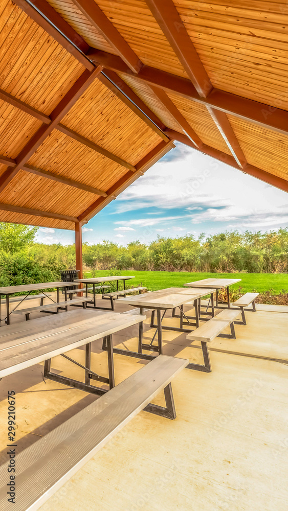 Vertical Close up view inside the pavilion of a park with tables and seats under the roof Vertical Close up view inside the pavilion of a park with tables and seats under the roof