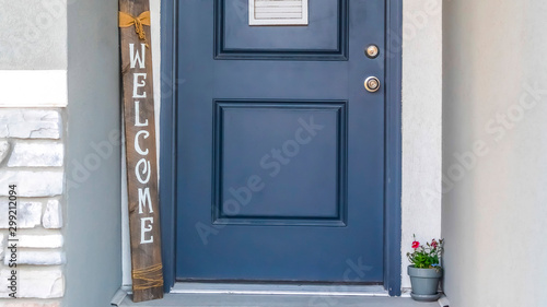 Panorama frame Blue front door of a home decorated with wreath welcome sign and potted flower photo