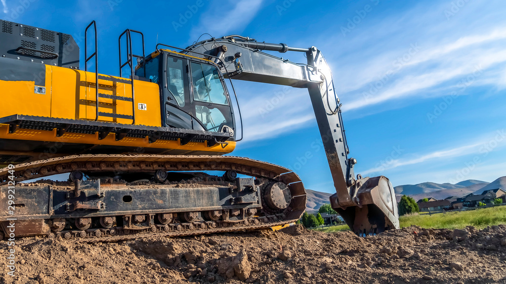 Obraz premium Panorama frame Yellow excavator with continuous tracks digging soil at a construction site