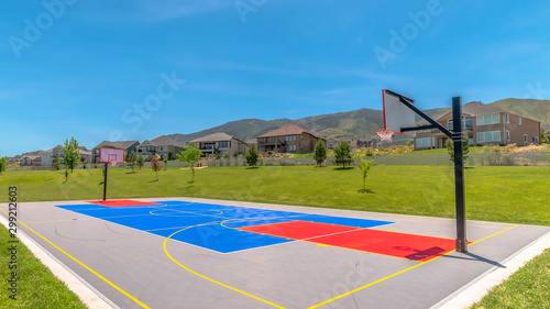 Panorama Basketball court at a park against houses and buildings viewed on a sunny day