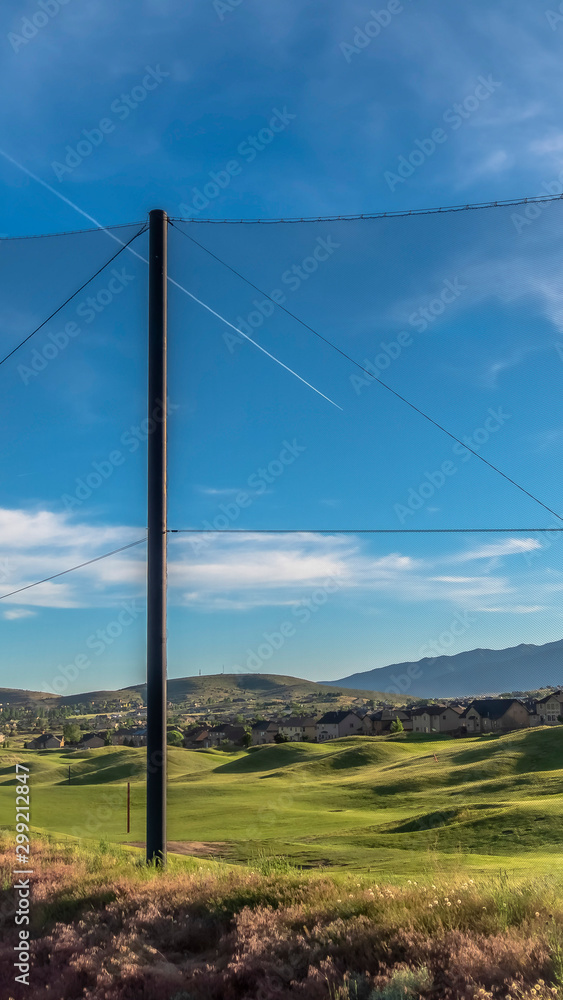Vertical frame Fence with golf course homes and mountain against blue sky on the other side Vertical frame Fence with golf course homes and mountain against blue sky on the other side