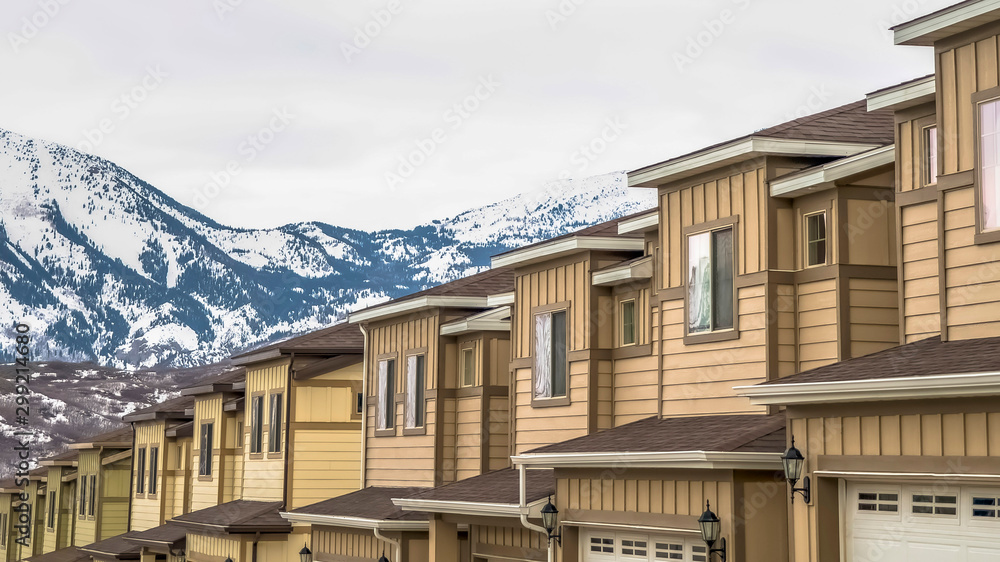 Panorama Townhouses with wall sidings and white garage doors against snowy mountain