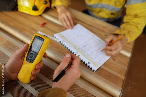 Construction miner hand holding checking at breathalyser breath alcohol testing equipment while his friend writing zero alcohol in the blood system on the daily sheet prior to work on mite site photo