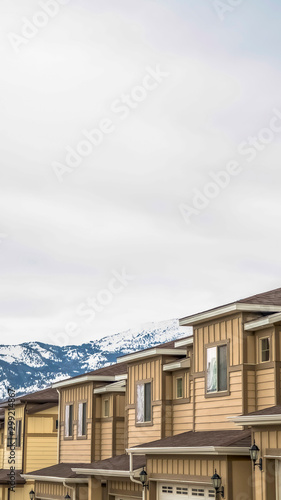 Vertical Townhouses with wall sidings and white garage doors against snowy mountain © Jason