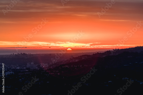 Sunset glowing over hills and city landscape.
