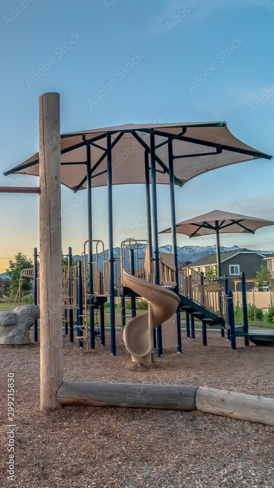 Vertical frame Childrens playground at a park with swings slides and umbrellas viewed at sunset