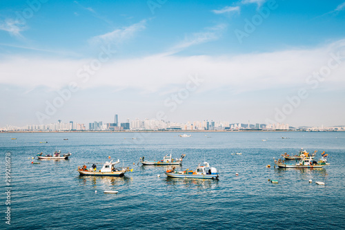 Incheon cityscape and sea with fishing boats from Sihwa tide embankment in Korea
