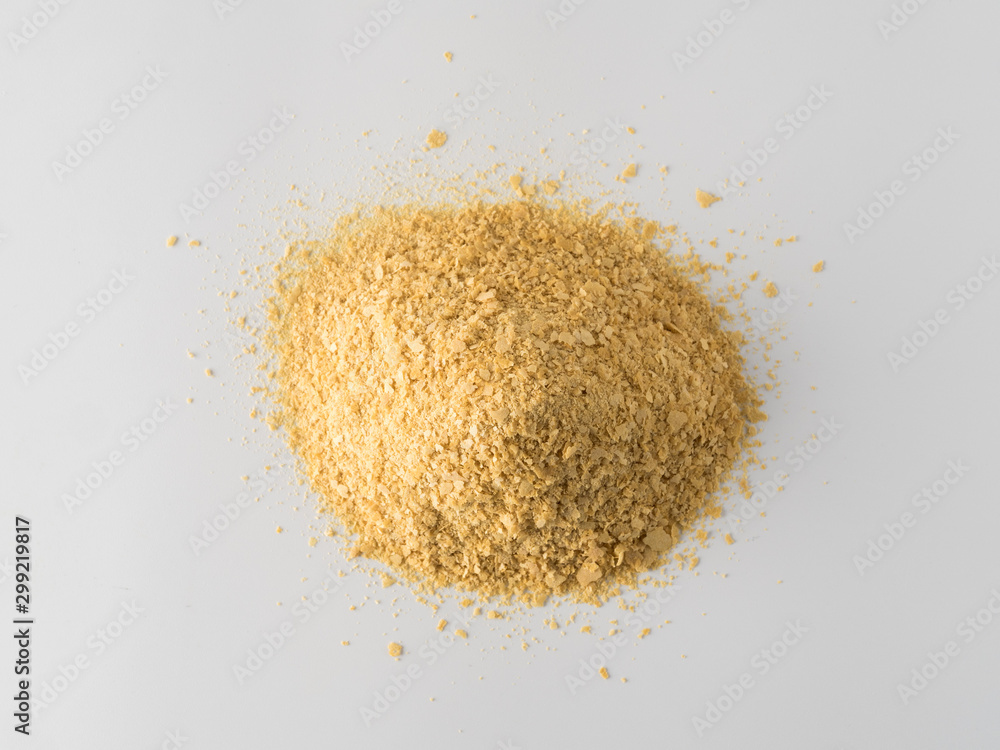 Nutritional yeast heap on white background. Nutritional inactive yeast top view. Copy space. Nutritional yeast is vegetarian superfood with cheese flavor, for healthy diet Nutritional yeast heap on white background. Nutritional inactive yeast top view. Copy space. Nutritional yeast is vegetarian superfood with cheese flavor, for healthy diet