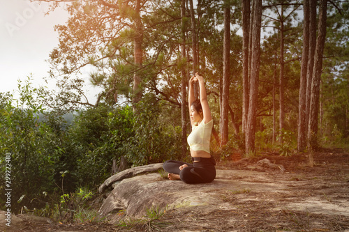 Young beautiful Asian woman practices yoga and meditates outdoor in the forest. Female doing yoga and meditate to relax and release stress. Weight Loss. Health care and lifestyle.