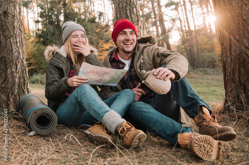 Travel couple camping with map having fun in the forest. Concept of trekking, adventure and seasonal vacation. © zadorozhna