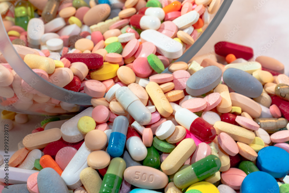 Many assorted pharmaceutical pills, tablets and capsules scattered out of a crystal containner. Medicine pharmaceutic concept. health care. health neglect. Many assorted pharmaceutical pills, tablets and capsules scattered out of a crystal containner. Medicine pharmaceutic concept. health care. health neglect.