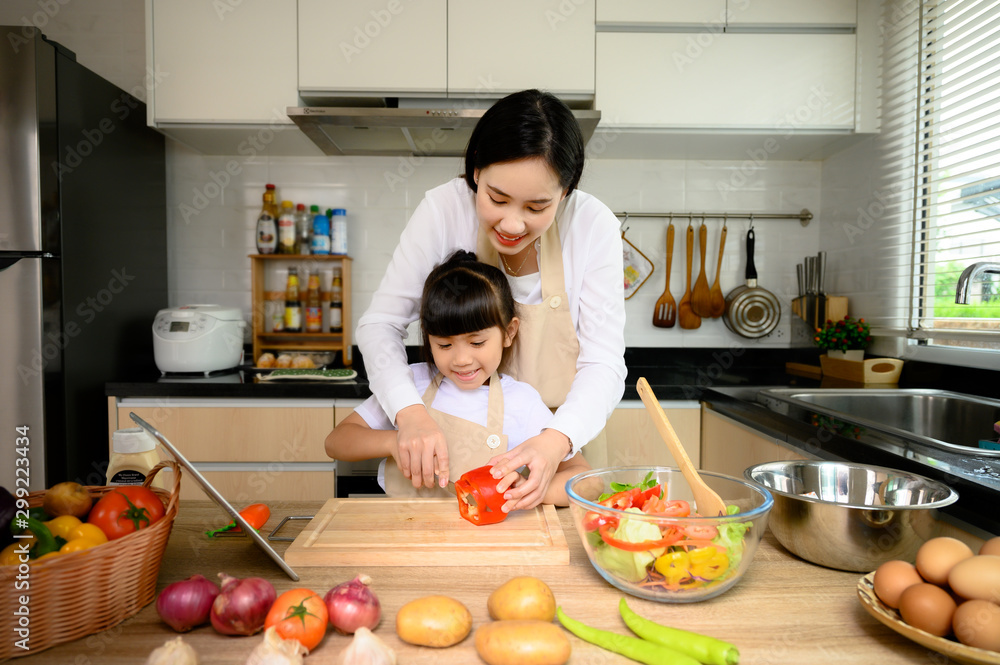 mother in course of teaching daughter in basic cooking, daughter learning cooking in home mother in course of teaching daughter in basic cooking, daughter learning cooking in home