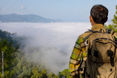 Young man with backpack looking misty autumn mountain hills, morning landscape view
