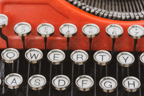 closeup of old portable red typewriter showing its qwerty keys.