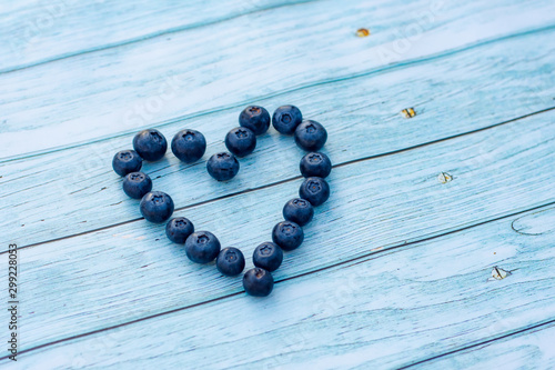 Superfood berries: blueberry heart on a wooden background.