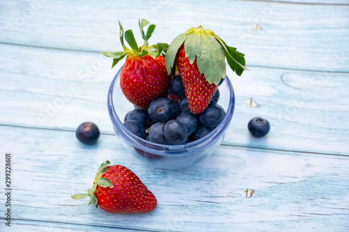 Blueberries amd strawberries in a bowl on a wooden background. Healthy lifestyle concept