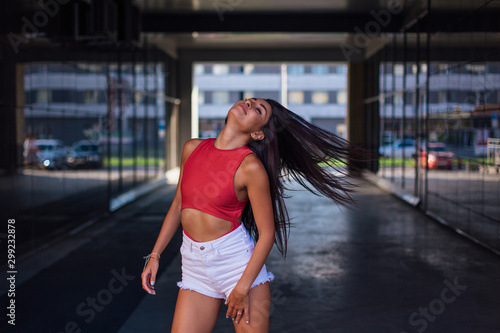 Young brunette woman dancing and shaking her hair in arch of building.