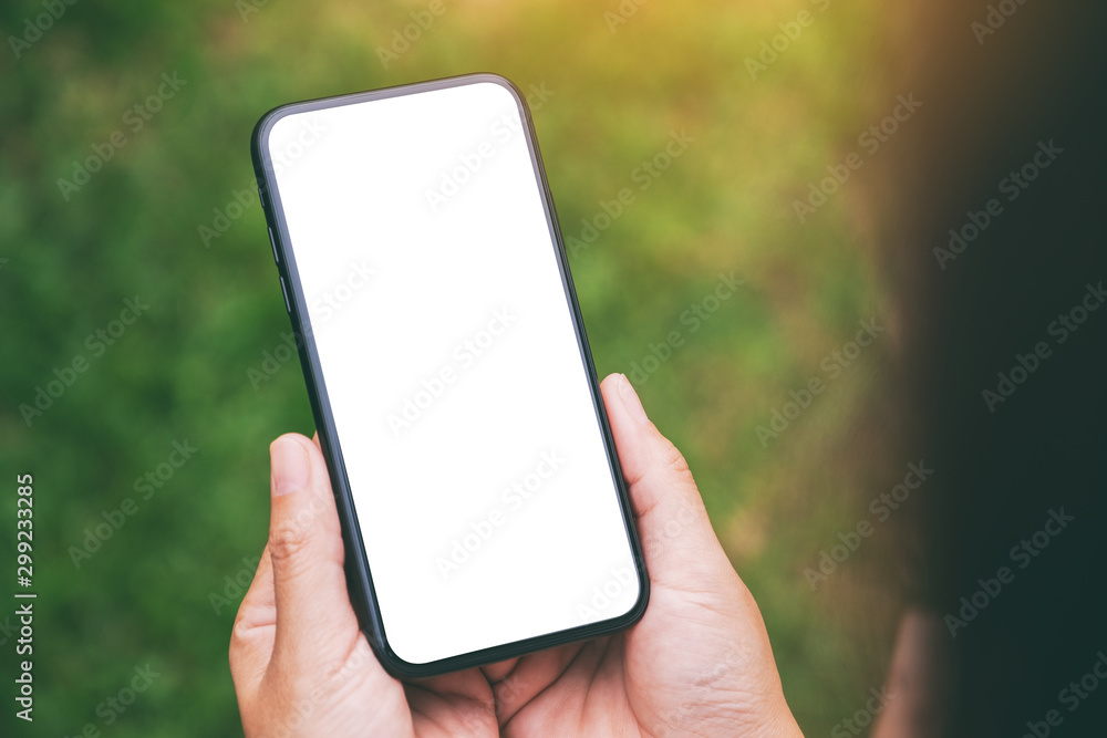 Mockup image of a woman holding black mobile phone with blank desktop screen with green nature background