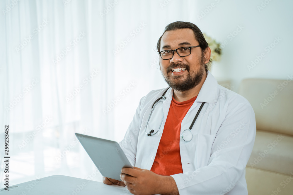 portrait of busy doctor using tablet pc in his office and smiling to camera portrait of busy doctor using tablet pc in his office and smiling to camera