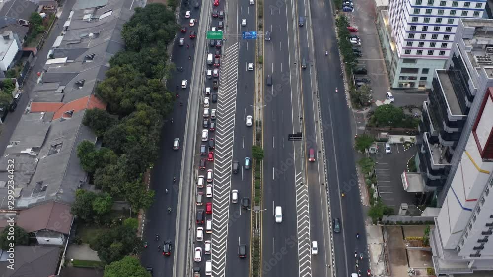 Aerial view above highway traffic in cityscape urban scene. Descending tilt up view over traffic lanes, Jakarta. Indonesia. Aerial view above highway traffic in cityscape urban scene. Descending tilt up view over traffic lanes, Jakarta. Indonesia.