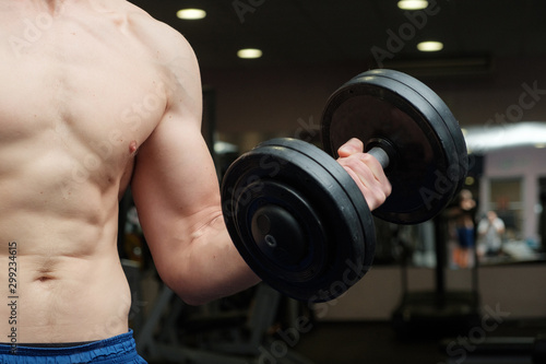 Part of a man's body with metal dumbbell on a blue background