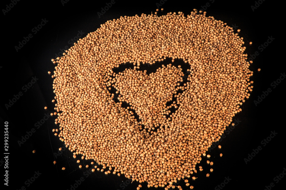 top view on heart sign made in big heap of dried coriander seeds top view on heart sign made in big heap of dried coriander seeds